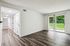 Bright and airy apartment with elegant wood flooring and sliding glass doors leading to a lush green outdoor space.