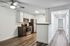 Modern kitchen in a stylish apartment features sleek stainless steel appliances and elegant wood flooring, leading to a bright hallway.
