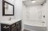 Modern bathroom with sleek fittings, featuring a stylish vanity and a pristine bathtub with built-in shelving.