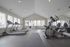 Modern fitness center with state-of-the-art treadmills, exercise bike, and weight machine, featuring large windows for natural light.