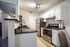 Modern kitchen with sleek stainless steel appliances, elegant black countertops, and contemporary lighting.