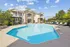 Luxurious apartment complex with a sparkling outdoor pool, surrounded by elegant lounge chairs and lush greenery, ideal for relaxation and entertainment.