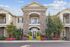 Charming two-story apartment complex with elegant stone facade, welcoming balconies, and vibrant landscaped gardens.