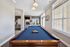 Charming entertainment space featuring a stylish pool table, cozy living area with a brick fireplace, and large windows for abundant natural light.