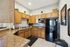 Modern kitchen with elegant wooden cabinets, sleek black appliances, and granite countertops, perfect for culinary creativity.