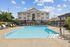 Inviting apartment complex with a spacious pool area surrounded by modern lounge chairs and lush greenery, perfect for relaxation.