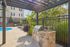 Charming outdoor space featuring a sleek grill area under a pergola, lush greenery, and a sparkling pool with sun loungers.