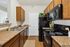 Charming modern kitchen with sleek black appliances, warm wooden cabinets, and a stylish countertop, perfect for culinary creations.