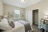 Cozy bedroom with soft lighting, featuring an elegant bed, art pieces on neutral walls, and a spacious closet for modern living.