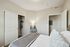 Inviting bedroom with soft lighting, elegant closet, and cozy bed dressed in luxurious linens.
