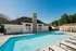 Inviting outdoor pool area with pristine water, stylish lounge chairs, and a charming clubhouse under a bright blue sky.