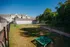 Spacious fenced backyard perfect for pets with lush greenery and nearby modern housing.