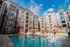 Modern apartment complex with a sparkling pool and sunlit patios, offering luxurious living and relaxation.