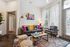 Chic living room with vibrant decor, featuring a cozy gray sofa adorned with colorful cushions, a modern floor lamp, and a large window offering ample natural light.