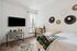 Bright bedroom with modern decor, featuring a stylish wall hanging, sleek workspace, and natural light from large windows.