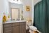 Chic bathroom featuring modern granite countertops, sleek gray cabinetry, and elegant green shower curtain.