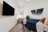 Cozy bedroom with a stylish navy bedspread, modern wall art, a sleek desk, and a mounted flat-screen TV.