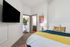 Inviting bedroom with a cozy bed adorned with colorful pillows, modern wall art, and a sleek wall-mounted TV.