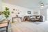 Inviting living room with modern decor, featuring a plush gray sectional sofa, stylish coffee table, and vibrant green plants for a cozy and chic atmosphere.