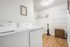 Bright and spacious laundry room with modern appliances, stylish wood flooring, and ample shelving for organization.