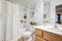 Charming bathroom with elegant floral accents, featuring a ruffled shower curtain, abundant greenery, and a sleek wooden vanity.