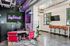 Chic office space with vibrant decor, featuring a neon 'Hey Friend!' sign, sleek modern furniture, and a stylish bar area with natural light.