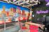 Vibrant interior with colorful cityscape mural and welcoming neon sign in a modern workspace.