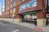 Contemporary brick apartment building exterior with large windows and modern signage, located on a bustling city street.