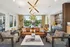 Luxurious and modern living room with a chic leather sofa, stylish lighting fixture, and a view of a serene outdoor patio.
