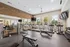Bright and modern fitness center with treadmills, strength machines, and free weights, featuring large windows for natural light and a sleek brick accent wall.