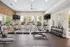 Contemporary fitness center with state-of-the-art treadmills, weight racks, and wall-mounted TVs, offering a vibrant workout space with natural light.