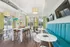 Bright and modern community room with sleek furniture, large windows, vibrant teal seating, and a ping-pong table for leisure activities.