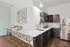 Modern kitchen featuring sleek dark cabinetry, elegant marble countertops, and stylish bar seating in a bright, contemporary space.