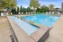Inviting outdoor pool area with crystal-clear water, surrounded by chic lounge chairs and vibrant umbrellas, exuding a relaxing and luxurious ambiance.