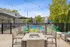 Chic outdoor patio with cozy seating, a fire pit, and string lights overlooking a refreshing pool, framed by modern architecture and lush greenery.