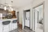 Contemporary kitchen with sleek granite countertop, stylish bar stools, and stacked washer-dryer in a cozy modern apartment.