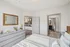 Bright and modern bedroom with sleek gray furnishings, featuring a view into a contemporary bathroom and stylish kitchen bar area.