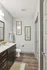 Contemporary bathroom with elegant wood flooring, sleek dark cabinetry, and stylish wall art for a modern touch.