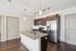 Modern kitchen with sleek granite countertops, dark wood cabinetry, stainless steel appliances, and elegant pendant lighting.
