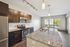 Modern kitchen featuring sleek granite countertops, stainless steel appliances, and dark wood cabinetry opening to a bright living area with large windows.