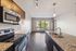 Elegant open-concept kitchen with granite countertops and modern appliances leading into a sunlit living area with large windows.