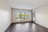 Bright and spacious unfurnished room featuring large windows, elegant dark wood flooring, and abundant natural light.