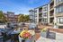 Chic apartment complex showcasing an inviting outdoor patio with comfortable seating, vibrant floral arrangements, and modern architecture under a clear blue sky.