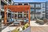 Chic apartment courtyard featuring modern seating under a stylish wooden pergola, surrounded by vibrant planters and contemporary architecture.