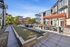 Chic apartment courtyard featuring stylish seating, modern pergolas, and a tranquil bocce ball court surrounded by lush greenery.