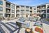 Inviting apartment complex courtyard with modern outdoor seating, vibrant flowers, and balconies overlooking the space, perfect for relaxation and gatherings.