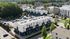 Modern apartment complex with sleek architecture, ample parking, and surrounded by lush greenery in a vibrant urban setting.