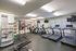 Modern fitness center with state-of-the-art treadmills, elliptical machines, and a variety of exercise equipment, featuring large windows for natural light.