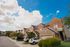 Charming suburban townhouses with modern brick exteriors under a bright blue sky, highlighting a serene neighborhood atmosphere.