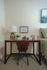 Cozy bedroom corner featuring a sleek wooden desk with a modern lamp, uplifting wall art, and stylish decor accents.